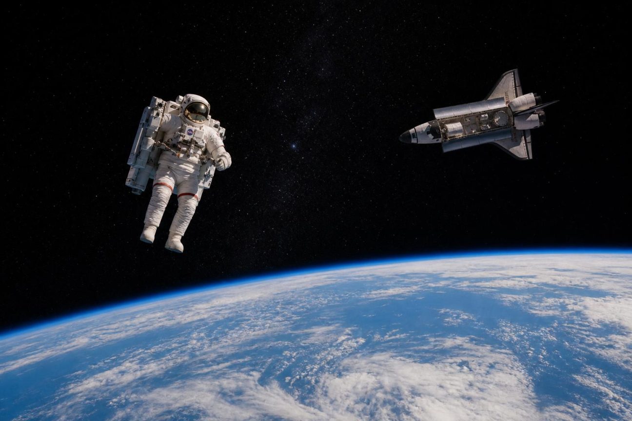 Astronaute flottant seul dans l'espace à grande distance d'une navette spatiale, la Terre visible derrière lui, équipé d'un grand sac dorsal à propulseurs.