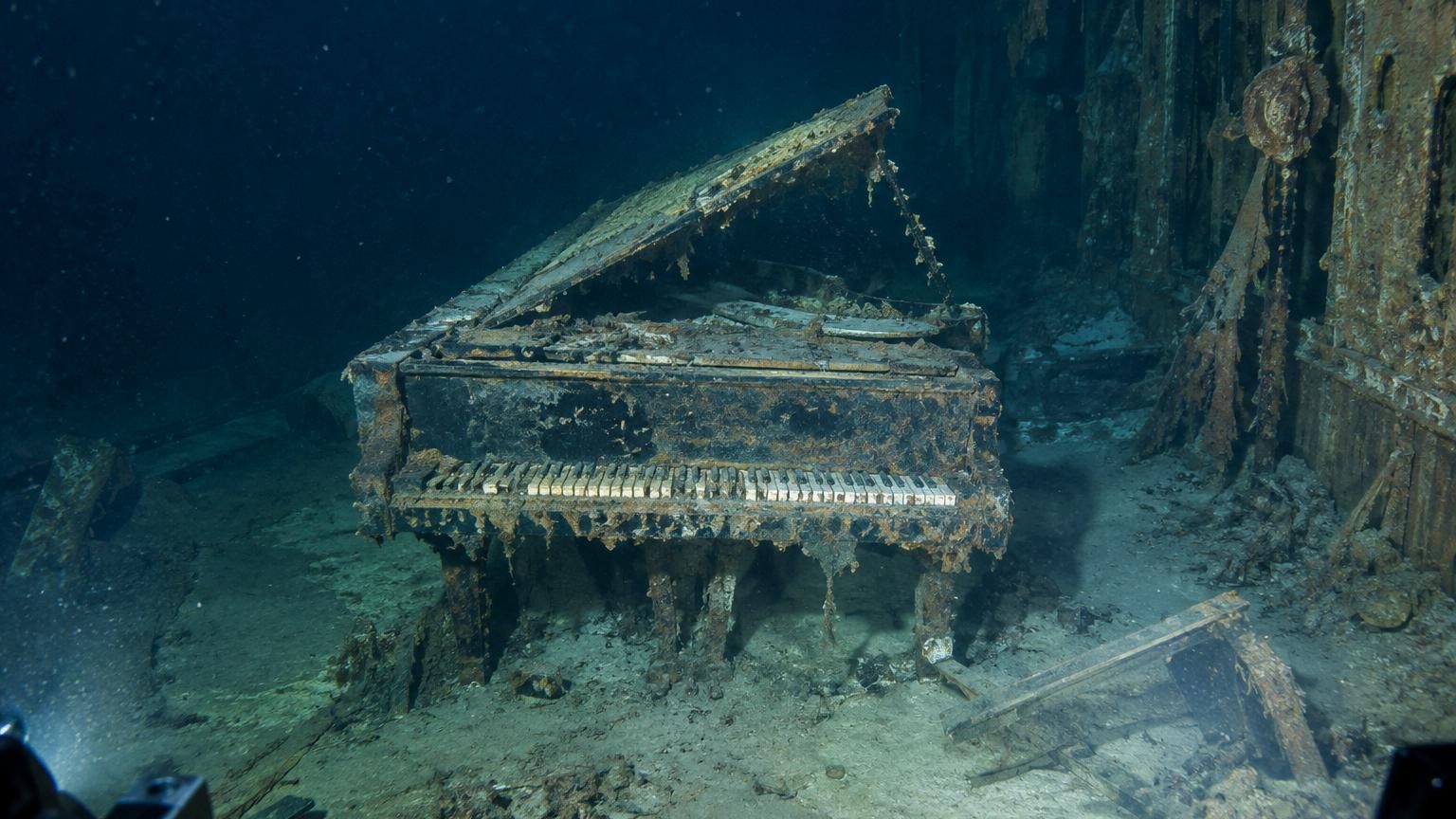 Plaque en fonte métallique d'un piano à queue reposant verticalement sur le fond marin du champ de débris du Titanic, entourée de sédiments océaniques