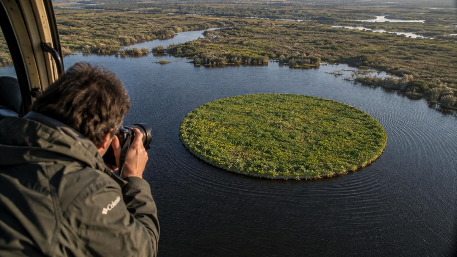 Vue aérienne d'une île circulaire végétalisée entourée par un lac rond aux eaux sombres, ressemblant à une pupille dans l'iris, au cœur du delta du Paraná en Argentine
